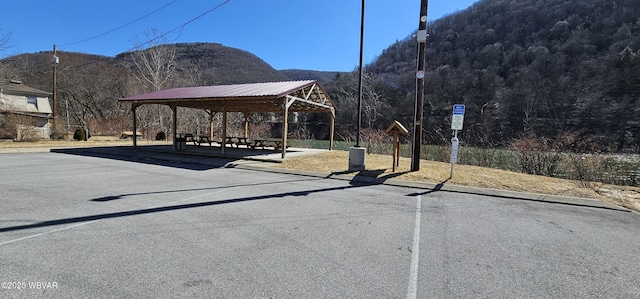 view of road featuring a wooded view, a mountain view, and curbs