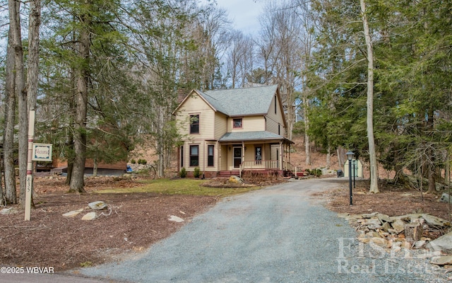 view of front facade featuring a porch, driveway, and roof with shingles