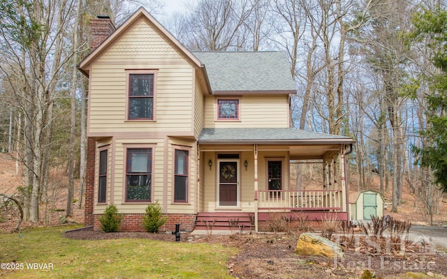 victorian home featuring covered porch, a chimney, roof with shingles, and a front yard