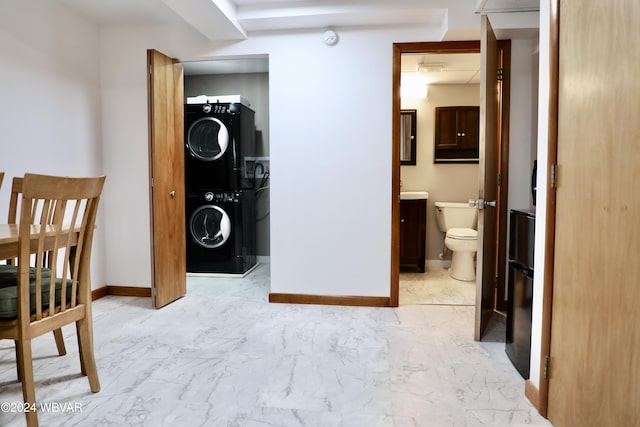 bedroom with stacked washer / drying machine and connected bathroom