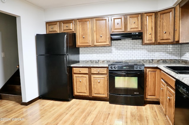 kitchen featuring sink, tasteful backsplash, light hardwood / wood-style flooring, and black appliances