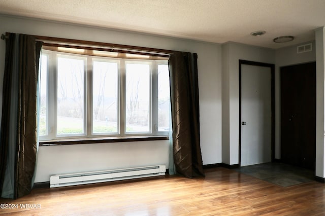 unfurnished bedroom with a baseboard radiator, a textured ceiling, and light wood-type flooring