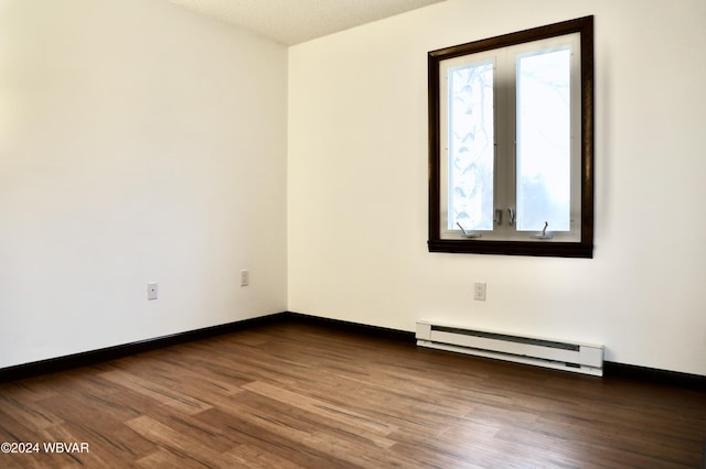 empty room featuring wood-type flooring, a textured ceiling, and a baseboard heating unit