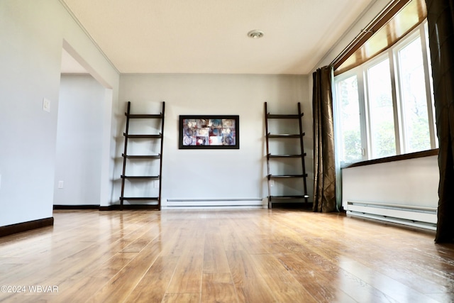 unfurnished room featuring light hardwood / wood-style flooring and a baseboard heating unit