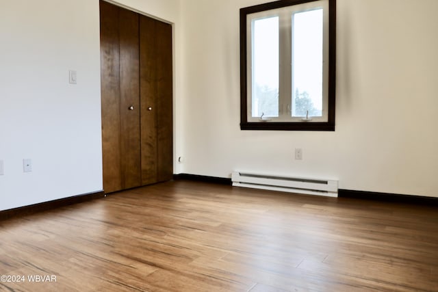 unfurnished bedroom featuring a baseboard radiator, a closet, and light hardwood / wood-style floors