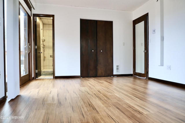 unfurnished bedroom with ensuite bathroom and light hardwood / wood-style floors