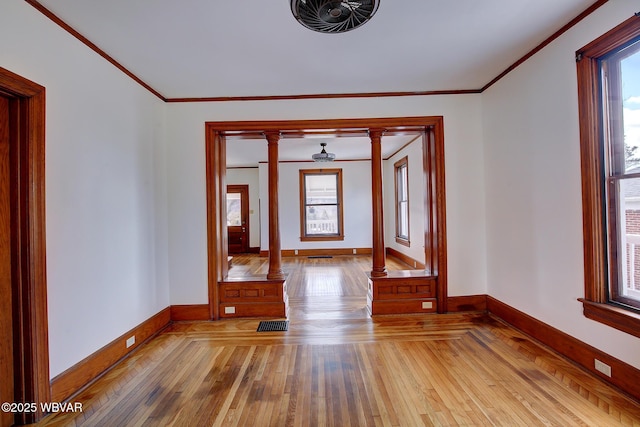 empty room featuring a wealth of natural light, decorative columns, and hardwood / wood-style floors
