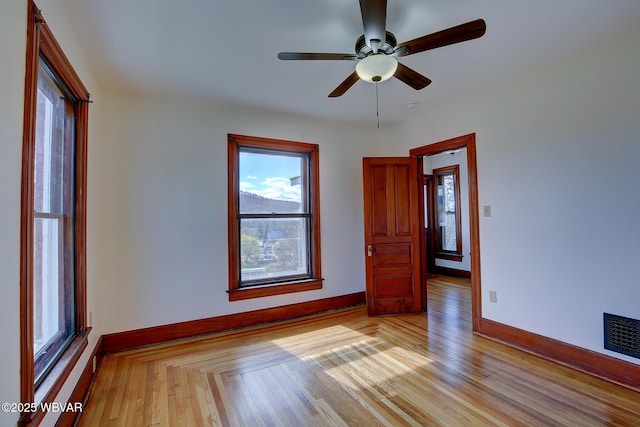 spare room featuring visible vents, baseboards, ceiling fan, and light wood-style floors