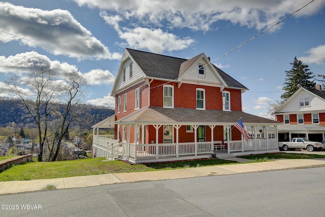 victorian-style house with covered porch, a front lawn, and brick siding