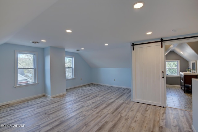 bonus room featuring light wood-style floors, visible vents, baseboards, and lofted ceiling