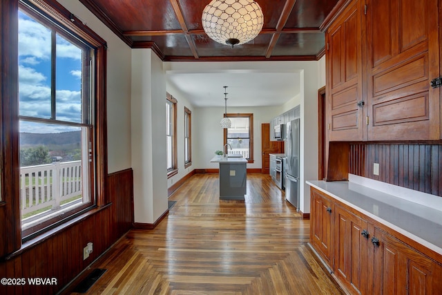 kitchen featuring visible vents, light countertops, freestanding refrigerator, wooden walls, and coffered ceiling