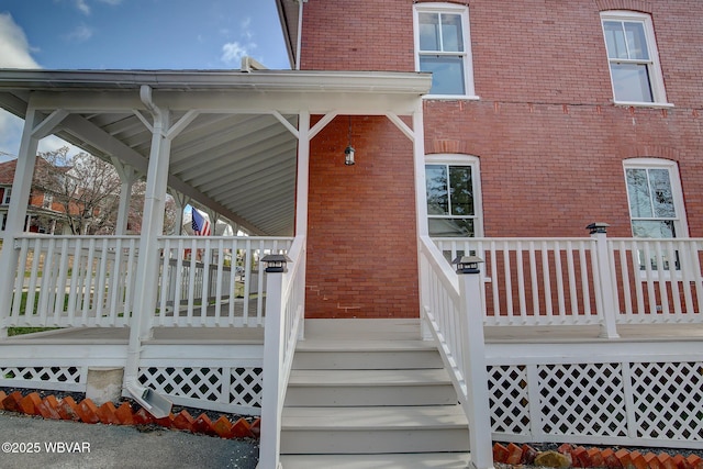 entrance to property with a porch and brick siding