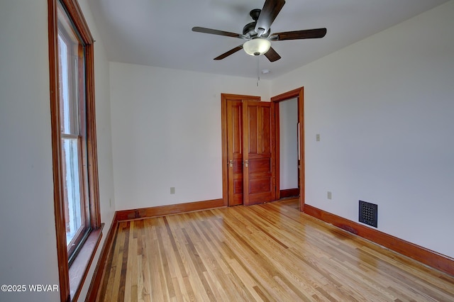 empty room with visible vents, baseboards, light wood finished floors, and ceiling fan