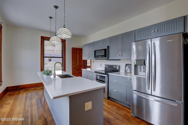 kitchen with baseboards, light countertops, gray cabinetry, appliances with stainless steel finishes, and a sink