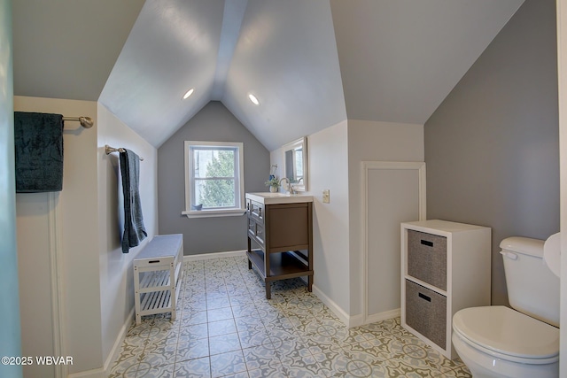 bathroom featuring vanity, baseboards, vaulted ceiling, and toilet