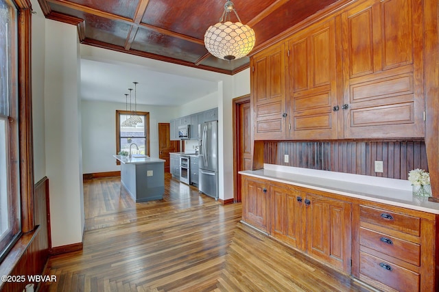 kitchen featuring light countertops, appliances with stainless steel finishes, a sink, and baseboards