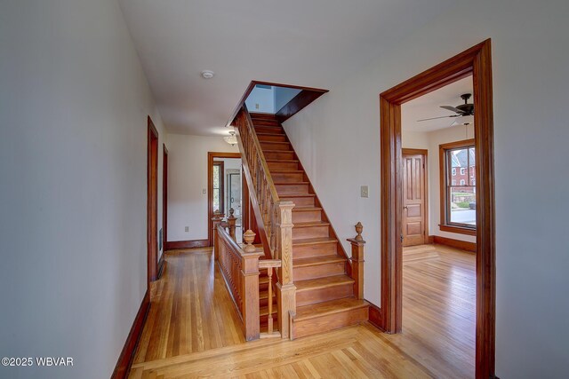 stairway featuring baseboards, a ceiling fan, and wood finished floors