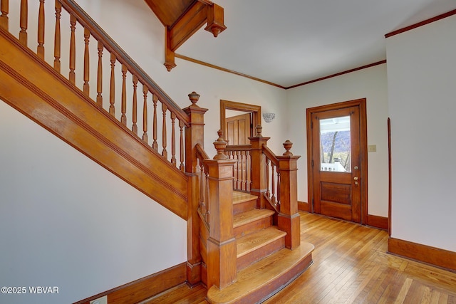 entryway with stairs, light wood finished floors, baseboards, and crown molding