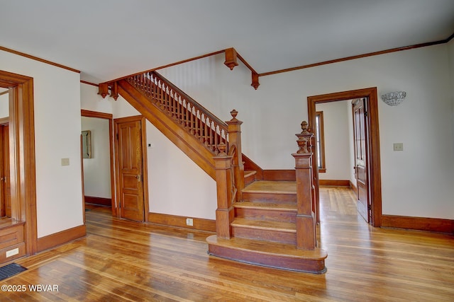 stairs with wood-type flooring, ornamental molding, and visible vents