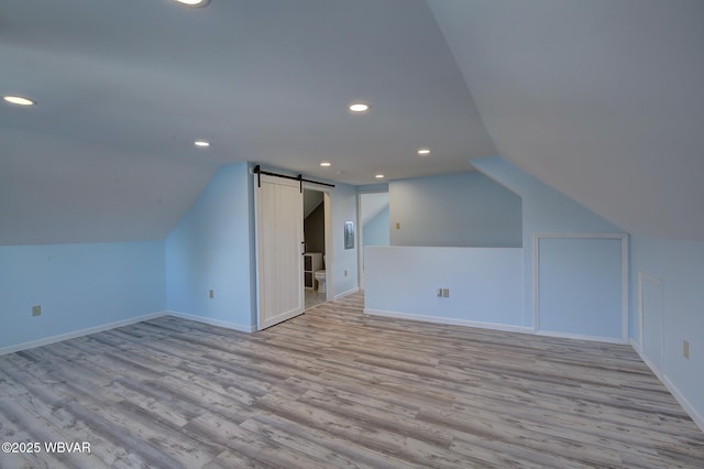 additional living space with a barn door, recessed lighting, lofted ceiling, and wood finished floors