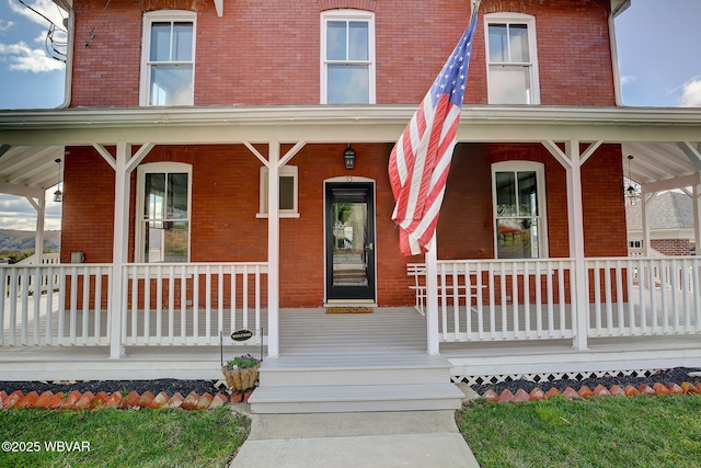 entrance to property featuring brick siding and covered porch