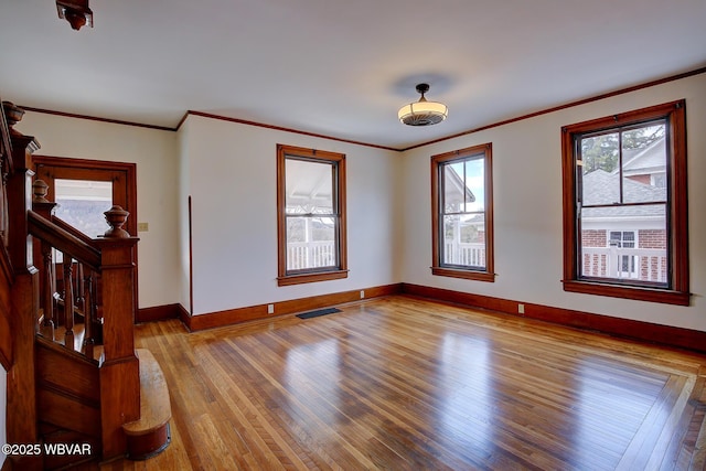 unfurnished room with baseboards, ornamental molding, stairs, visible vents, and wood finished floors