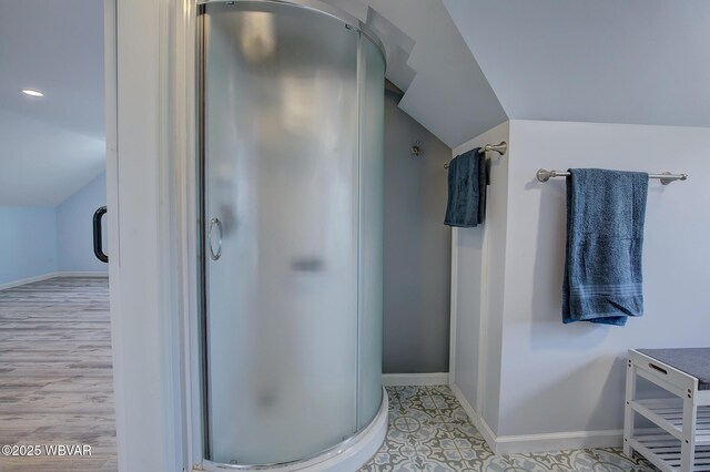 full bathroom featuring a stall shower, baseboards, and vaulted ceiling