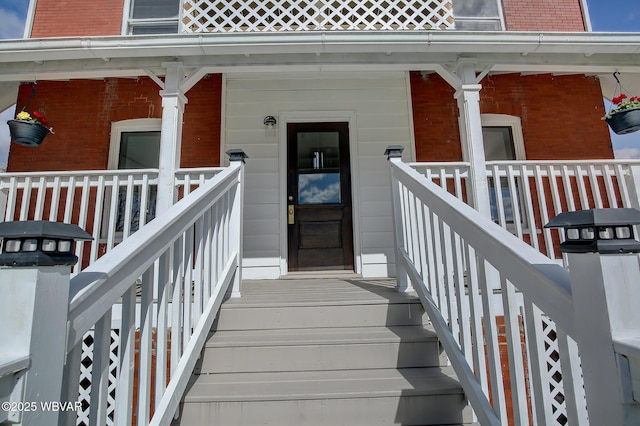 property entrance featuring brick siding and covered porch