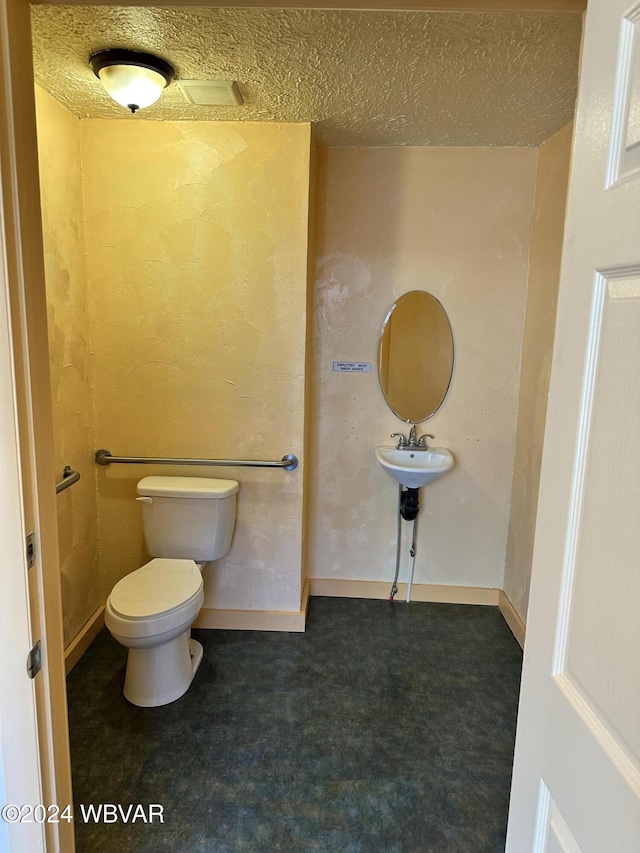 bathroom with toilet and a textured ceiling