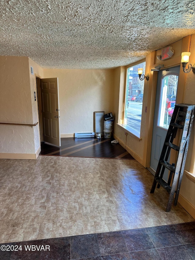 interior space with a textured ceiling and baseboard heating