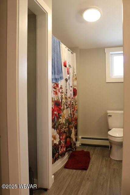 full bath featuring a baseboard heating unit, a shower with shower curtain, toilet, and wood finished floors