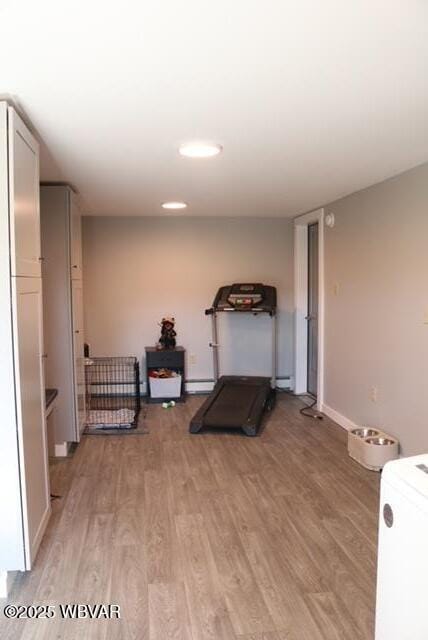 exercise area with light wood-style floors and a baseboard radiator