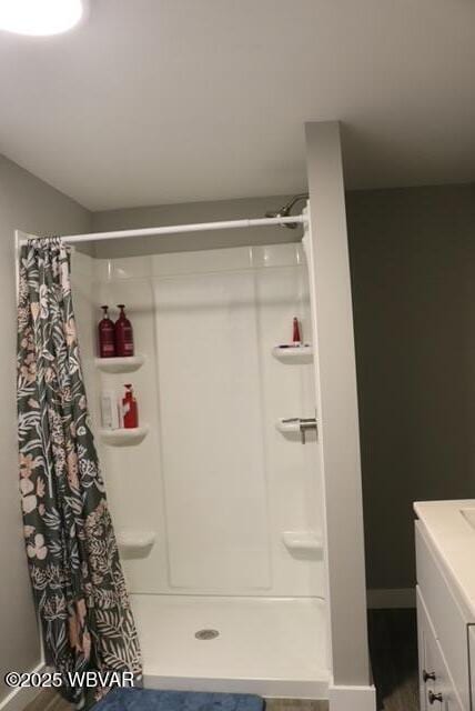 full bath with a stall shower, vanity, baseboards, and wood finished floors