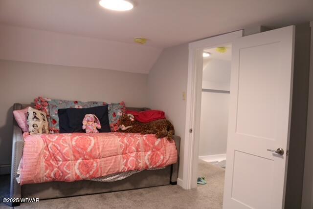 carpeted bedroom featuring a baseboard radiator and vaulted ceiling