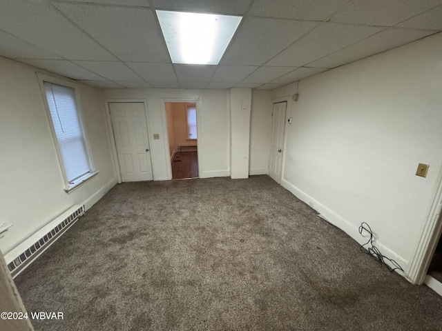 carpeted empty room with a drop ceiling and a baseboard heating unit