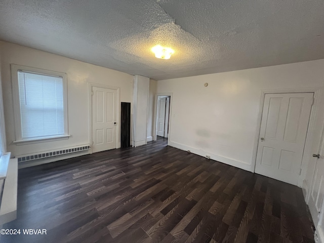 spare room with a textured ceiling, dark hardwood / wood-style floors, and a baseboard heating unit