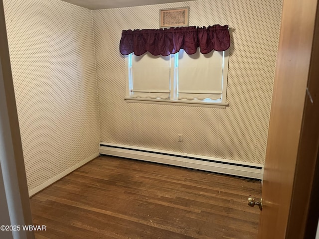 spare room with dark hardwood / wood-style flooring and a baseboard heating unit