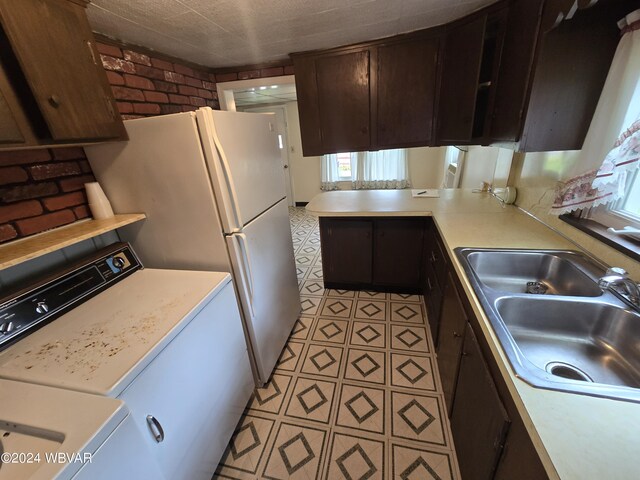 kitchen featuring kitchen peninsula, brick wall, sink, light tile patterned floors, and washer / clothes dryer