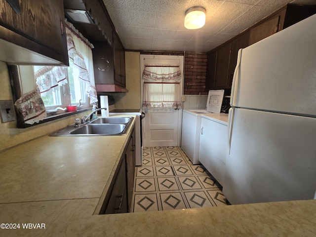 kitchen with dark brown cabinets, white refrigerator, washer / dryer, and sink