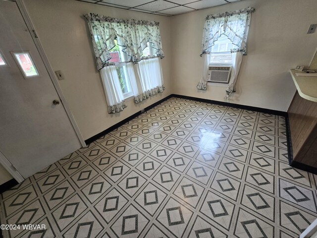 unfurnished dining area with light tile patterned floors, a paneled ceiling, cooling unit, and a healthy amount of sunlight