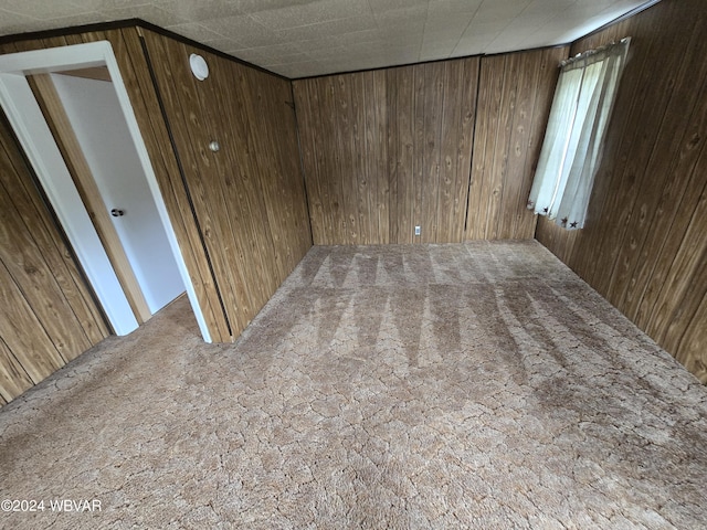 unfurnished room with wooden walls and carpet floors