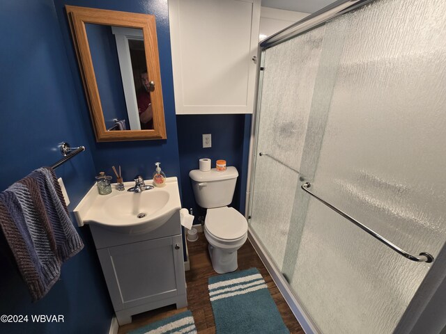 bathroom with hardwood / wood-style floors, vanity, toilet, and a shower with door