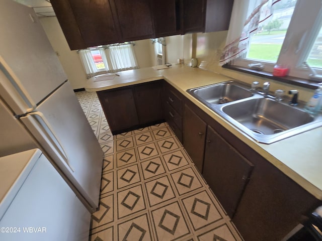 kitchen featuring dark brown cabinetry, white refrigerator, plenty of natural light, and sink