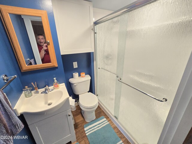 bathroom featuring hardwood / wood-style floors, vanity, toilet, and an enclosed shower