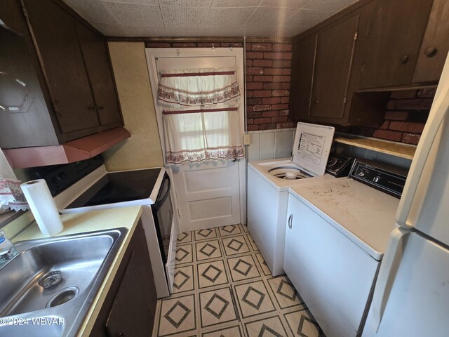 kitchen with dark brown cabinetry, stainless steel electric range oven, sink, separate washer and dryer, and white refrigerator