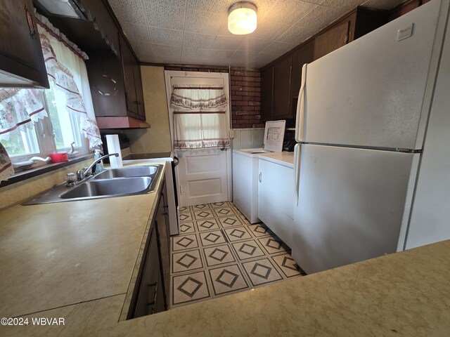 kitchen with washer / dryer, dark brown cabinetry, and white refrigerator