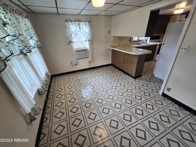 kitchen with kitchen peninsula, a paneled ceiling, cooling unit, white fridge, and light tile patterned flooring