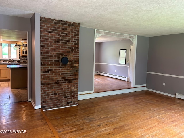 575 Steele Hill Rd, Sugar Run, PA 18846 - unfurnished room with baseboard heating, a textured ceiling, wood finished floors, baseboards, and a sink