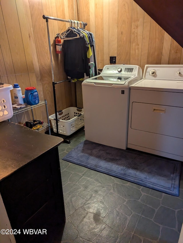 clothes washing area with separate washer and dryer and wooden walls