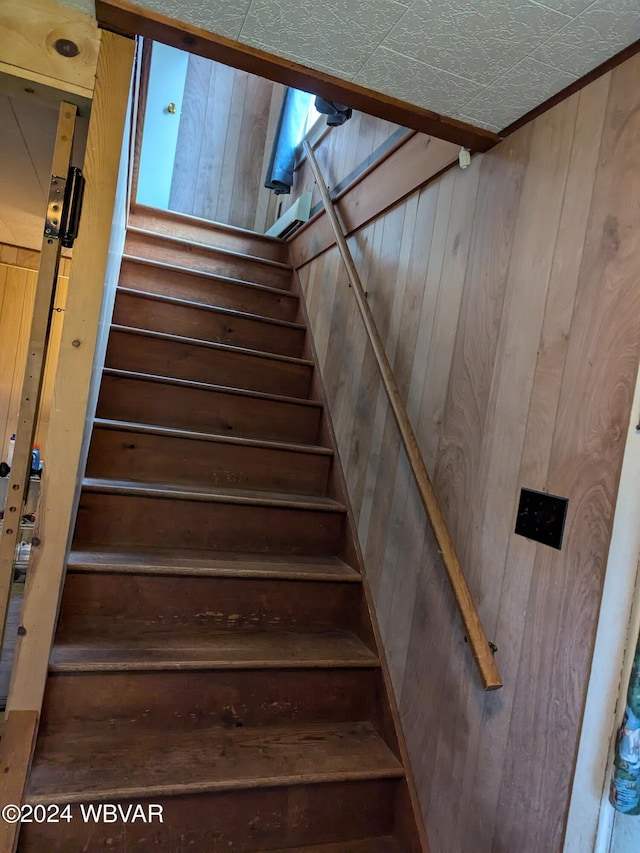 staircase featuring wooden walls